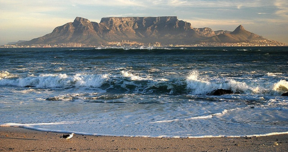 7 days The West Coast Table Mountain seen across a dark blue ocean with waves, from a sandy beach in the foreground.